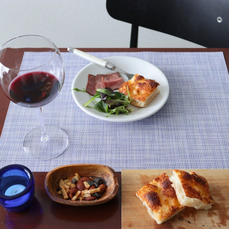 「Chilewich Mini Basketweave ランチョンマット(ペリウィンクル)」を使った大人のディナースタイル。ワイン、ナッツ、パンが並び、落ち着いた食卓を演出。