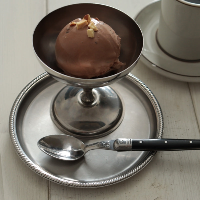 MOTTAのサンマルコソーサーに乗ったアイスクリームカップ。細やかな縁取りが施されたシルバーのソーサーは、イタリアのクラシカルなデザインを現代的なスタイルで再現しています。この耐久性の高いステンレス製ソーサーは、デザートや小さな食事をエレガントにサービングするのに最適です。